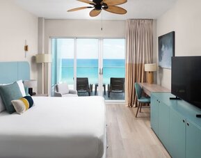 Oceanfront guest room with a private balcony and king bed at Sherry Frontenac Oceanfront Hotel.