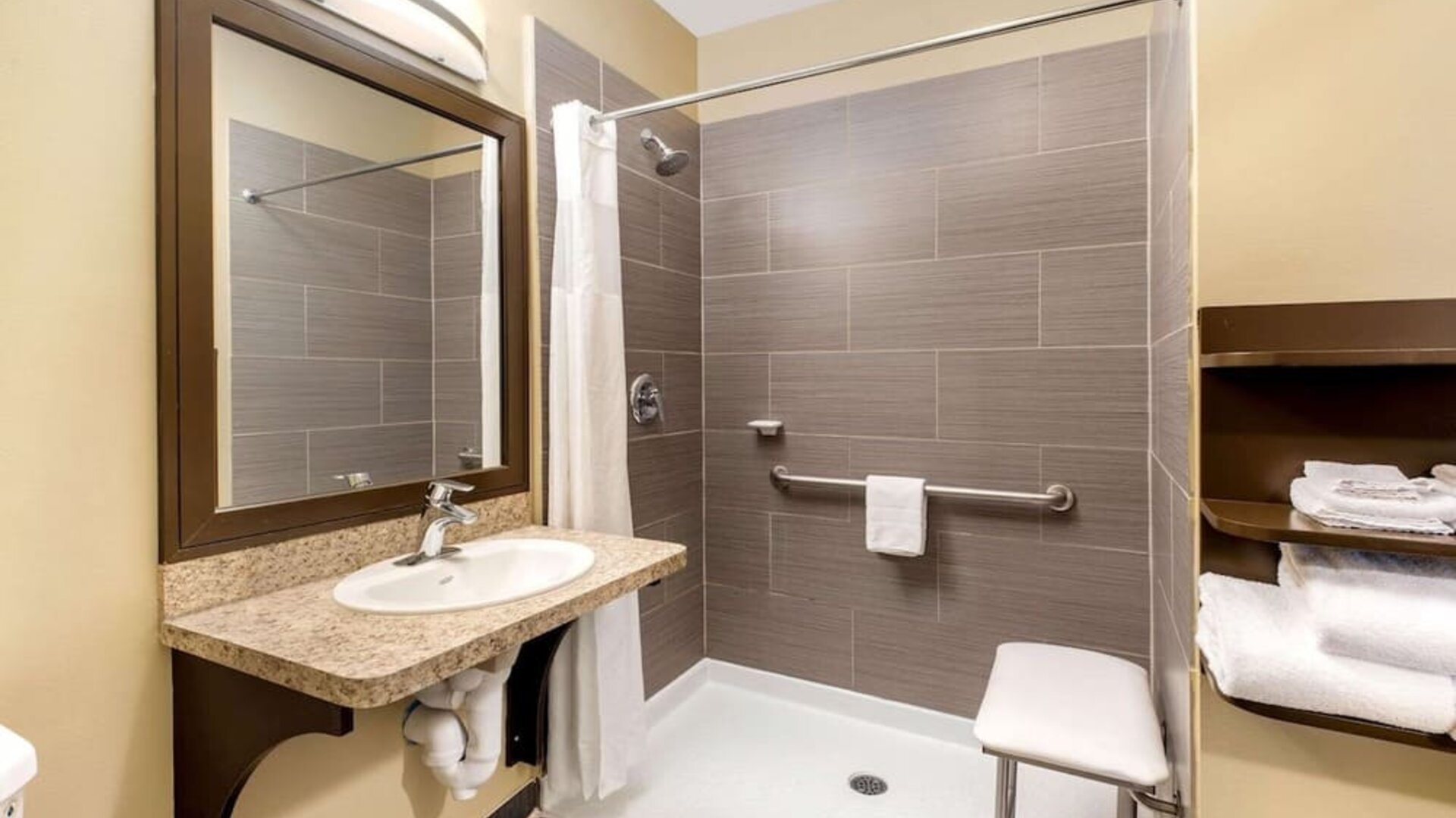 Accessible guest bathroom with a roll-in shower at La Quinta Inn & Suites By Wyndham Oshawa.