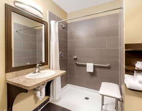 Accessible guest bathroom with a roll-in shower at La Quinta Inn & Suites By Wyndham Oshawa.