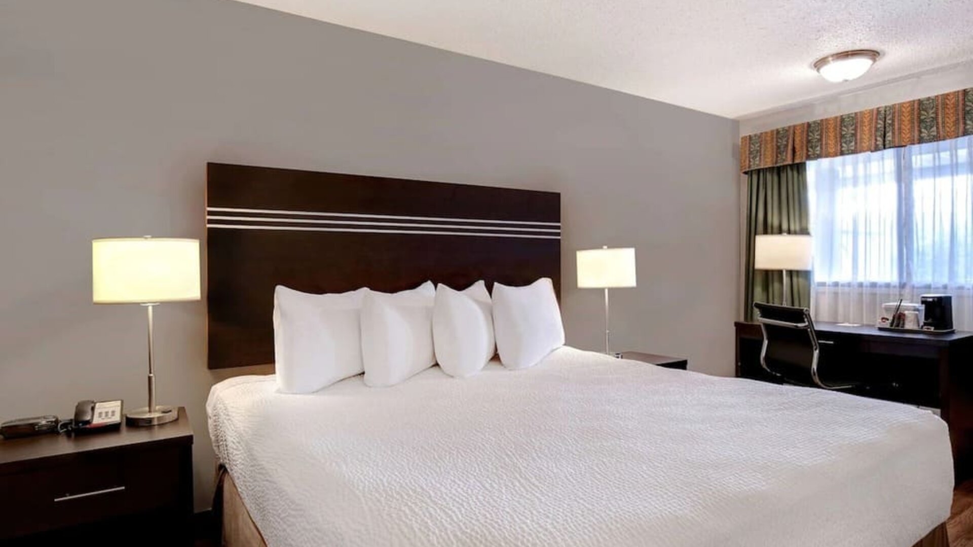 Guest room with a king bed and work desk at Days Inn Vernon.