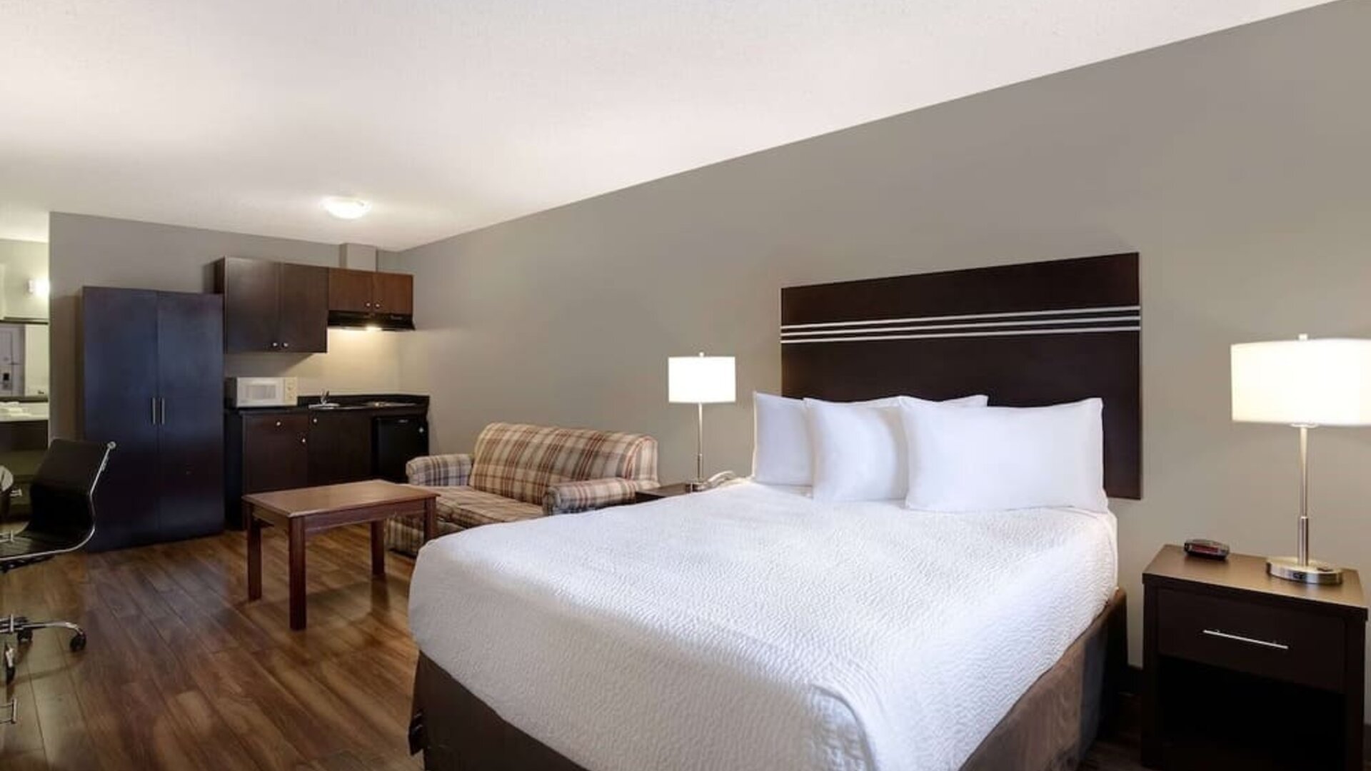 Guest room with a king bed, sofa, and kitchenette at Days Inn Vernon.