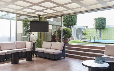 Indoor lounge with cushioned seating, floor-to-ceiling windows and views of the outdoor pool at Hotel Casa Blanca.