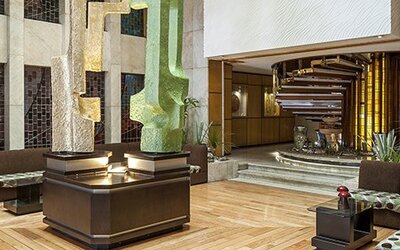 Modern hotel lobby with decorative sculptures, wood flooring and cushioned seating areas at Hotel Casa Blanca.