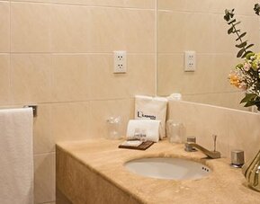 Bathroom vanity with marble countertop, fresh flowers, toiletries and neatly folded towels at Hotel Lepanto.