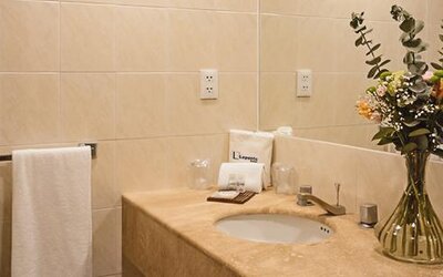 Bathroom vanity with marble countertop, fresh flowers, toiletries and neatly folded towels at Hotel Lepanto.
