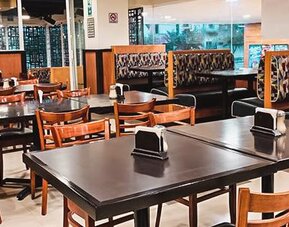 Restaurant seating area with wooden tables, upholstered booths and large windows overlooking the street at Hotel Lepanto.