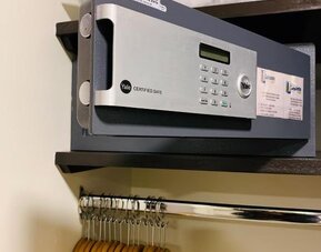 In-room wardrobe with electronic safe, hanging rail and wooden clothes hangers at Hotel Lepanto.