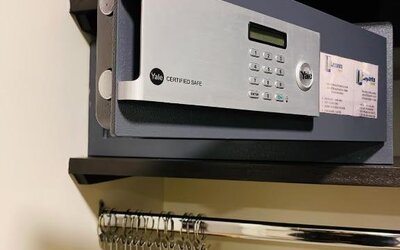 In-room wardrobe with electronic safe, hanging rail and wooden clothes hangers at Hotel Lepanto.