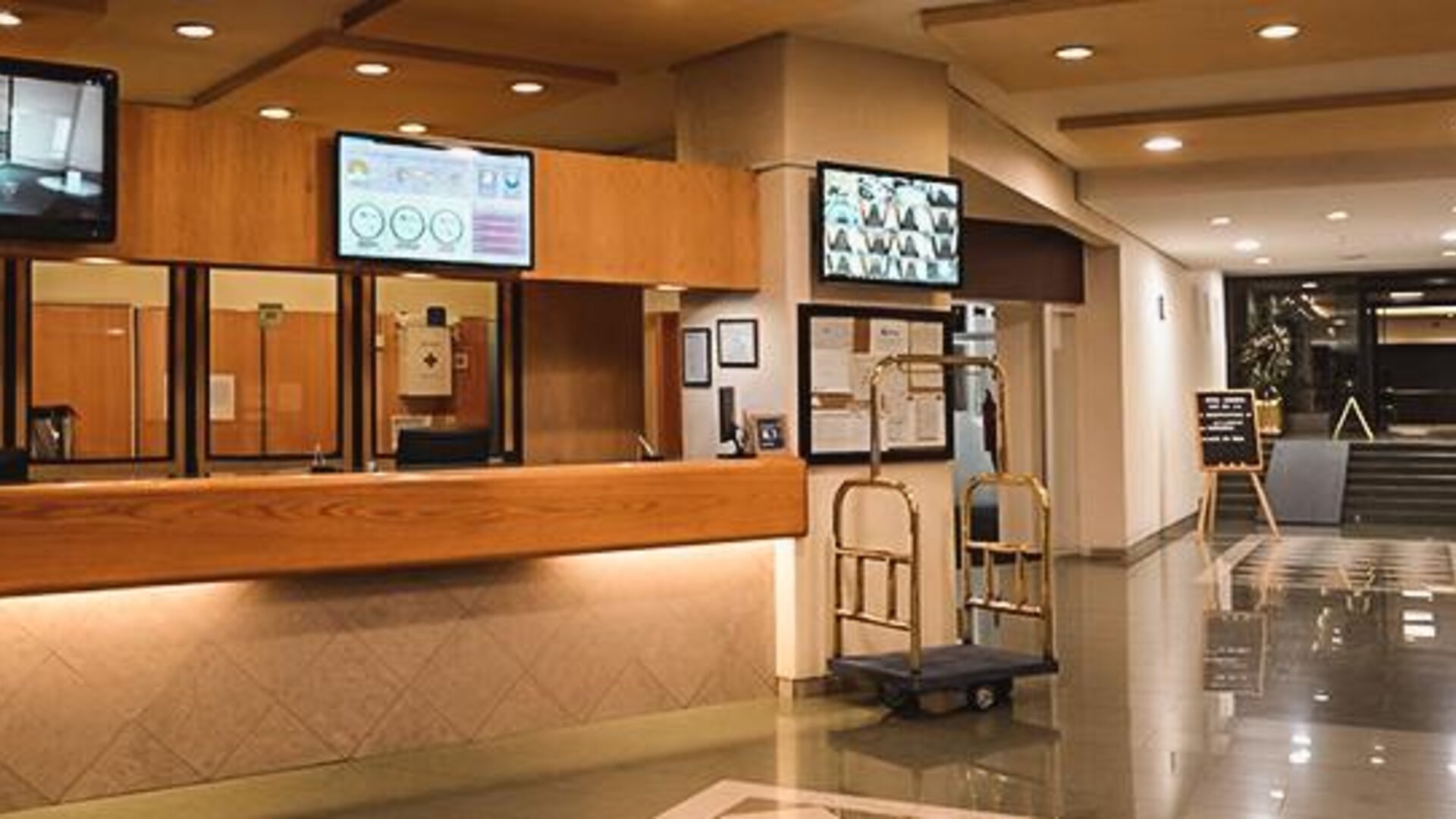 Spacious hotel reception area with front desk, luggage carts and polished tile flooring at Hotel Lepanto.
