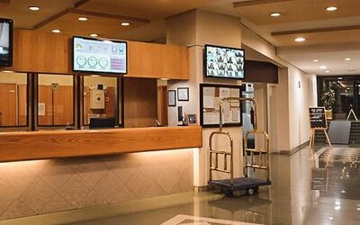 Spacious hotel reception area with front desk, luggage carts and polished tile flooring at Hotel Lepanto.