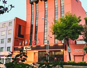 Hotel exterior with entrance, flags and landscaped trees along the surrounding city street at Hotel Lepanto.