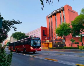 Hotel exterior with prominent signage viewed from a tree-lined street and passing city bus at Hotel Lepanto.