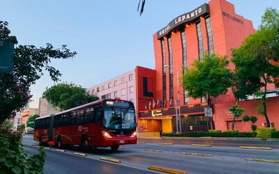 Hotel exterior with prominent signage viewed from a tree-lined street and passing city bus at Hotel Lepanto.