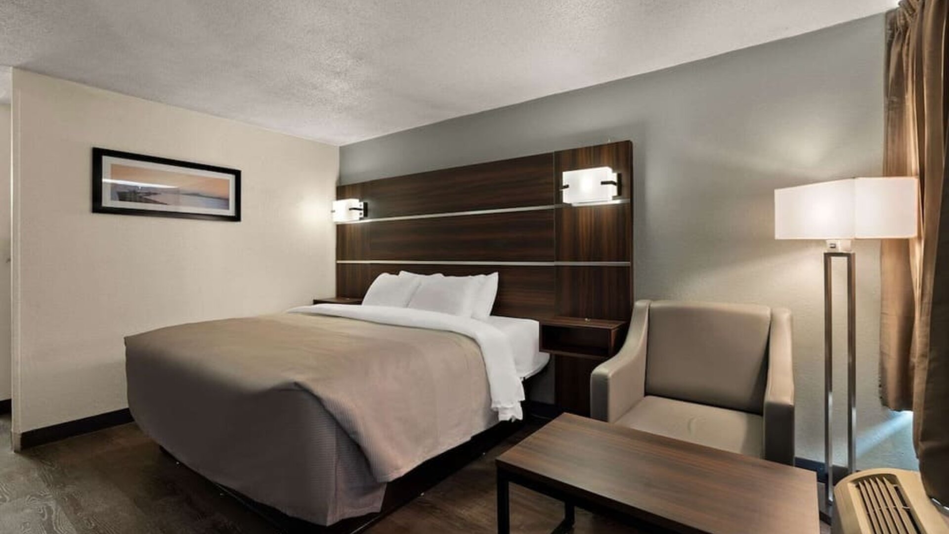 Guest room with one king bed, armchair, coffee table and floor lamp beside the window at Quality Inn Yemassee - Point South I-95.