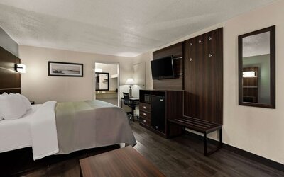 King guest room with wall-mounted TV, workspace, mini fridge and luggage bench at Quality Inn Yemassee - Point South I-95.