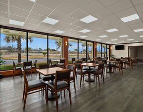 Bright breakfast dining area with wooden tables, large windows and views of the hotel grounds at Quality Inn Yemassee - Point South I-95.