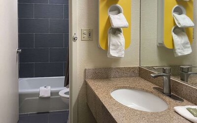 Bathroom with granite vanity, bathtub and shower combination, towel storage and modern fixtures at Econo Lodge Yemassee.