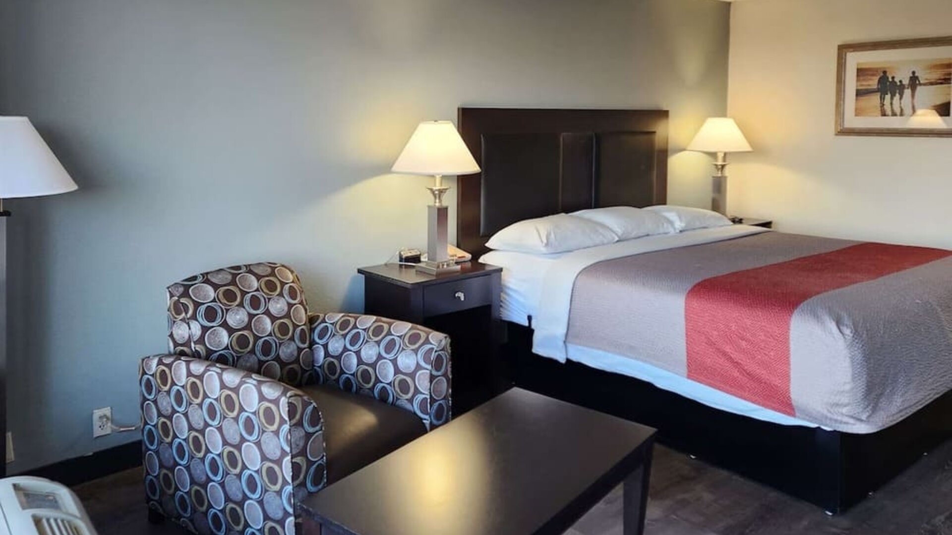 King guest room with seating area, coffee table and bedside lamps beside the bed at Econo Lodge Yemassee.
