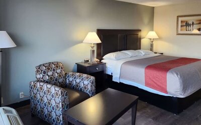 King guest room with seating area, coffee table and bedside lamps beside the bed at Econo Lodge Yemassee.