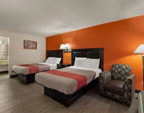 Guest room with two double beds, accent wall, armchair and open vanity area at Econo Lodge Yemassee.