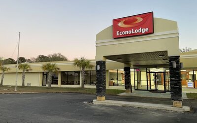Hotel entrance with covered porte cochère, illuminated Econo Lodge sign and palm trees at Econo Lodge Yemassee.