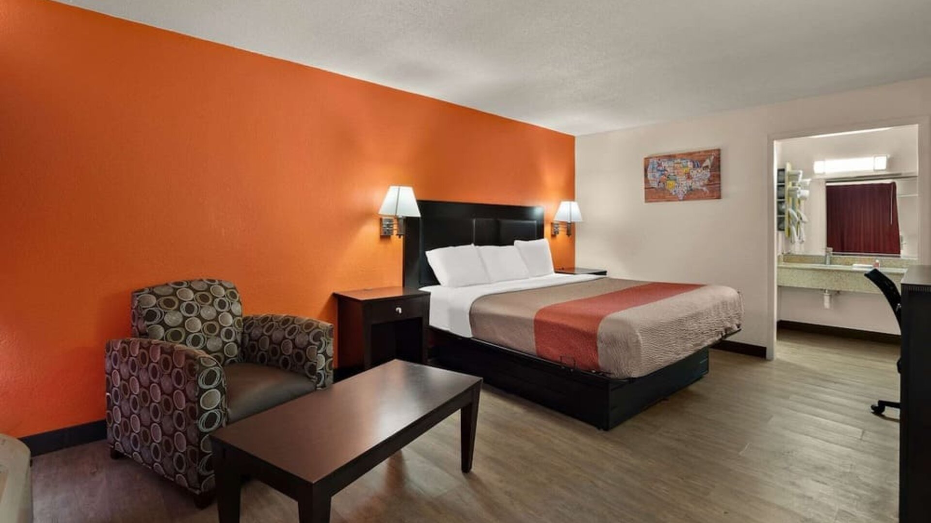 Spacious king guest room with armchair, coffee table and open vanity area at Econo Lodge Yemassee.