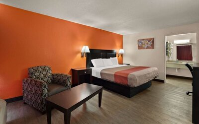Spacious king guest room with armchair, coffee table and open vanity area at Econo Lodge Yemassee.