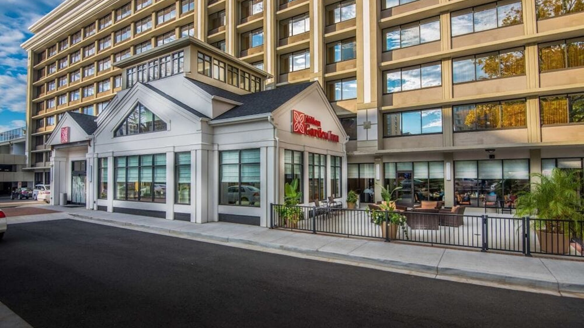 Exterior view of the Hilton Garden Inn featuring modern architecture, main entrance, and outdoor patio seating.