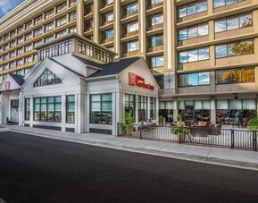 Exterior view of the Hilton Garden Inn featuring modern architecture, main entrance, and outdoor patio seating.