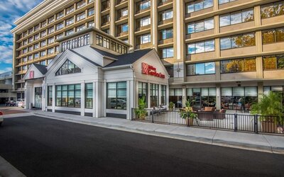 Exterior view of the Hilton Garden Inn featuring modern architecture, main entrance, and outdoor patio seating.