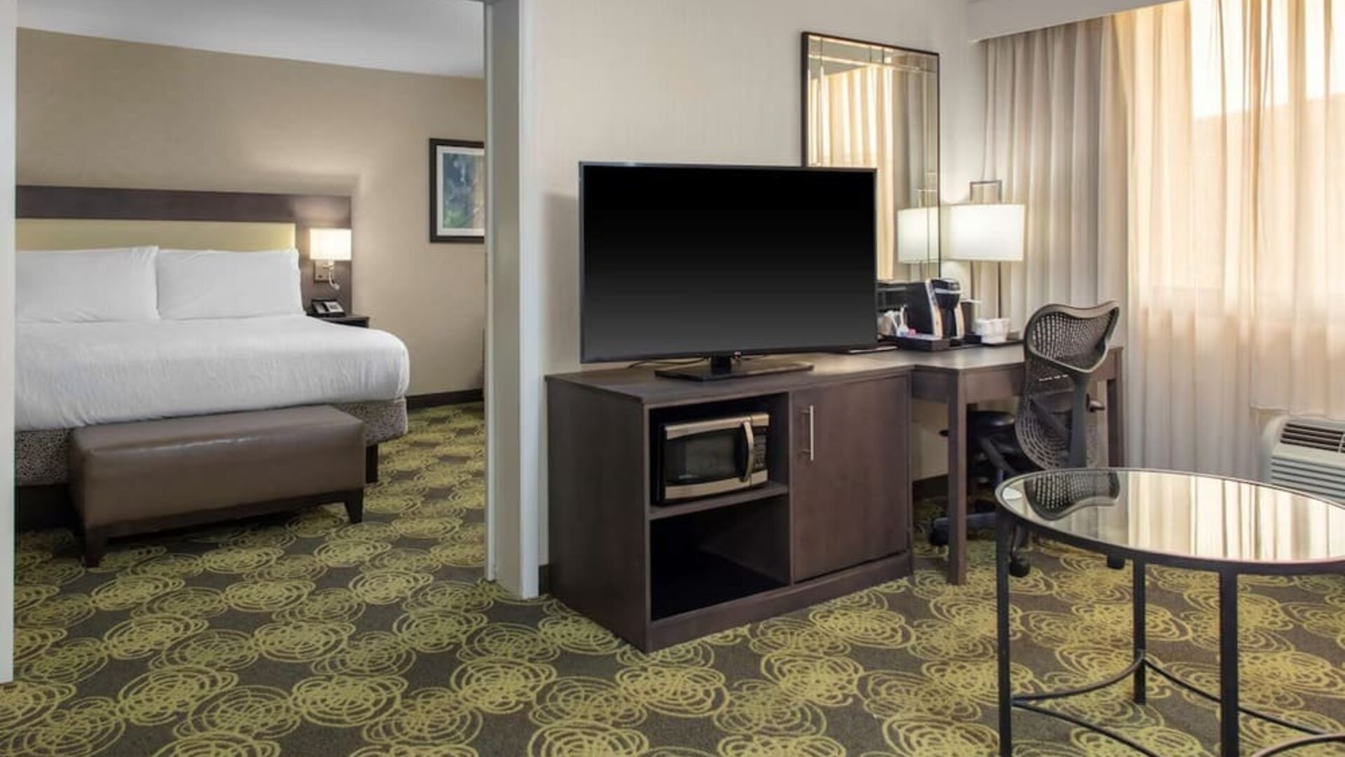 King guest room with comfortable bed, large TV, ergonomic work desk, coffee maker, and microwave for added convenience.