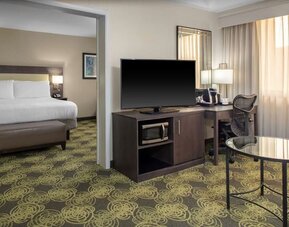 King guest room with comfortable bed, large TV, ergonomic work desk, coffee maker, and microwave for added convenience.