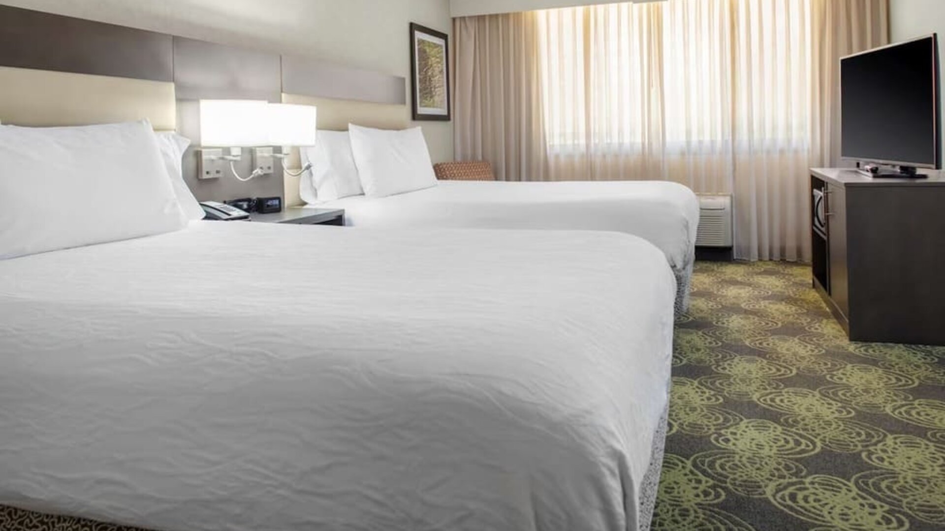 Guest room with two queen beds, HDTV, work desk, microwave, and spacious layout ideal for families or groups.