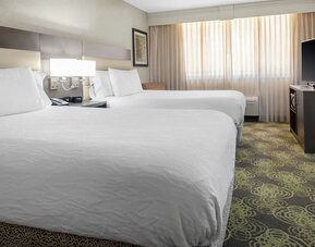 Guest room with two queen beds, HDTV, work desk, microwave, and spacious layout ideal for families or groups.