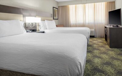 Guest room with two queen beds, HDTV, work desk, microwave, and spacious layout ideal for families or groups.