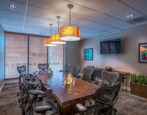 Private meeting room with large conference table, ergonomic chairs, TV, and natural light for business gatherings.