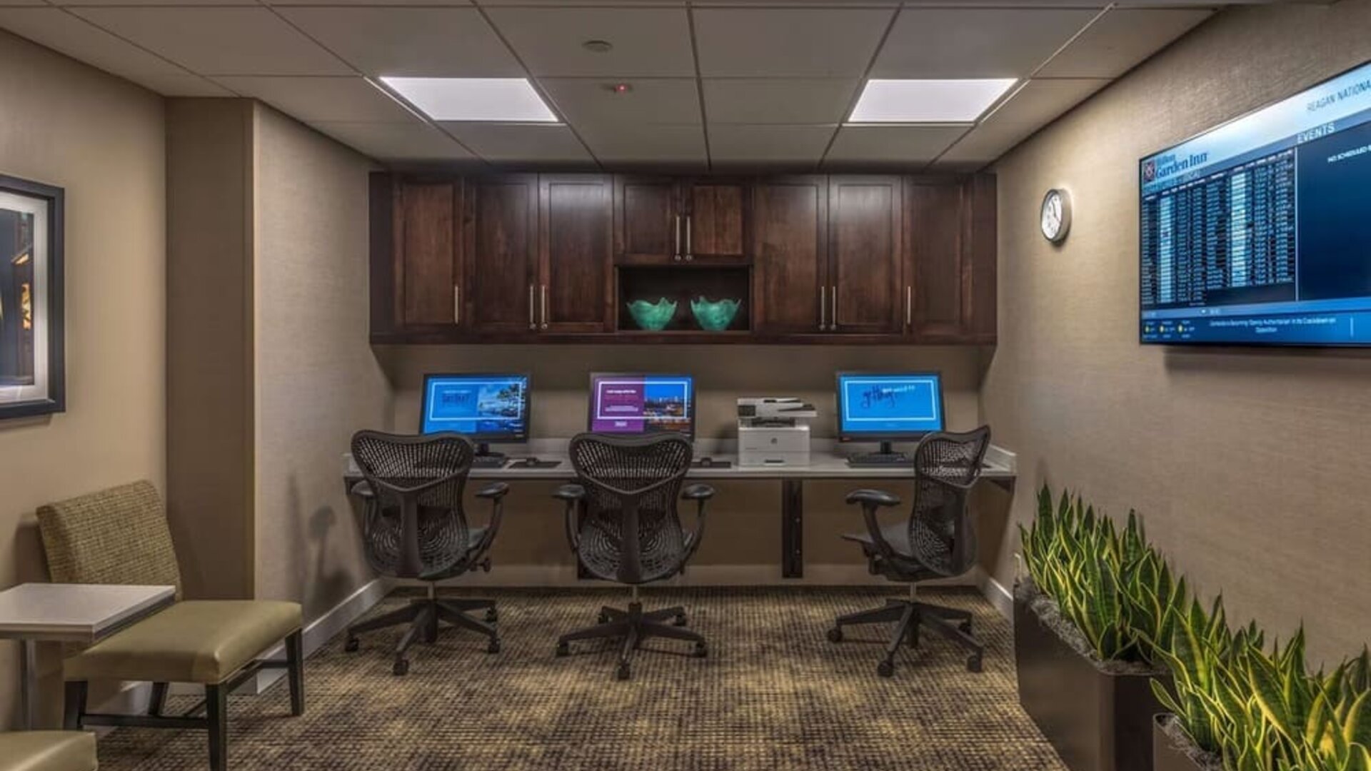 Business center with three desktop computers, printer, ergonomic chairs, and workspace for guests needing to stay productive.