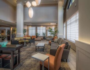 Spacious hotel lobby with comfortable seating, high ceilings, natural light, and relaxing areas for work or conversation.