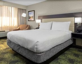 Spacious king suite with separate bedroom, living area, HDTV, work desk, microwave, and comfortable seating.