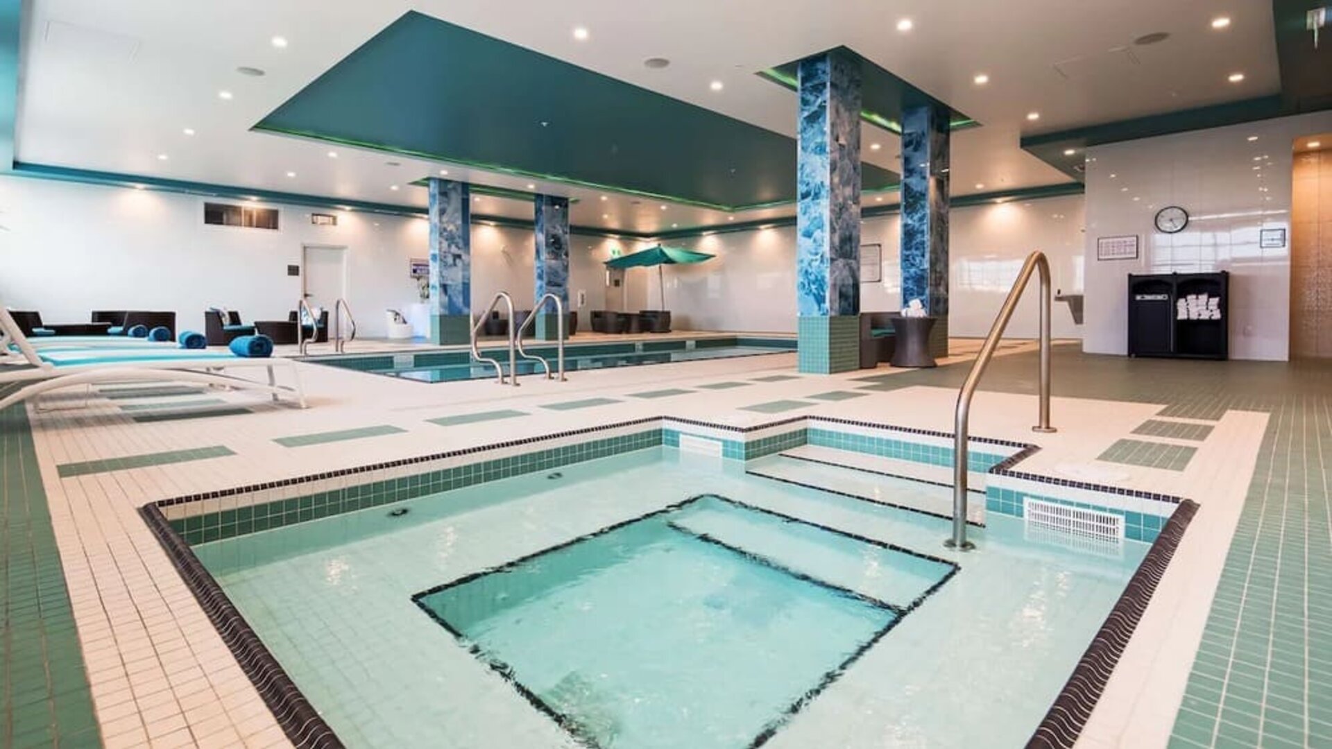Relaxing indoor pool with jacuzzi and lounge chairs at Executive Residency By Best Western.