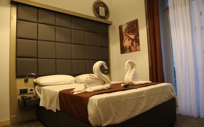 Cozy double guest room with plush bedding, decorative towel swans and natural light at Dolce Vita Rooms & Breakfast.