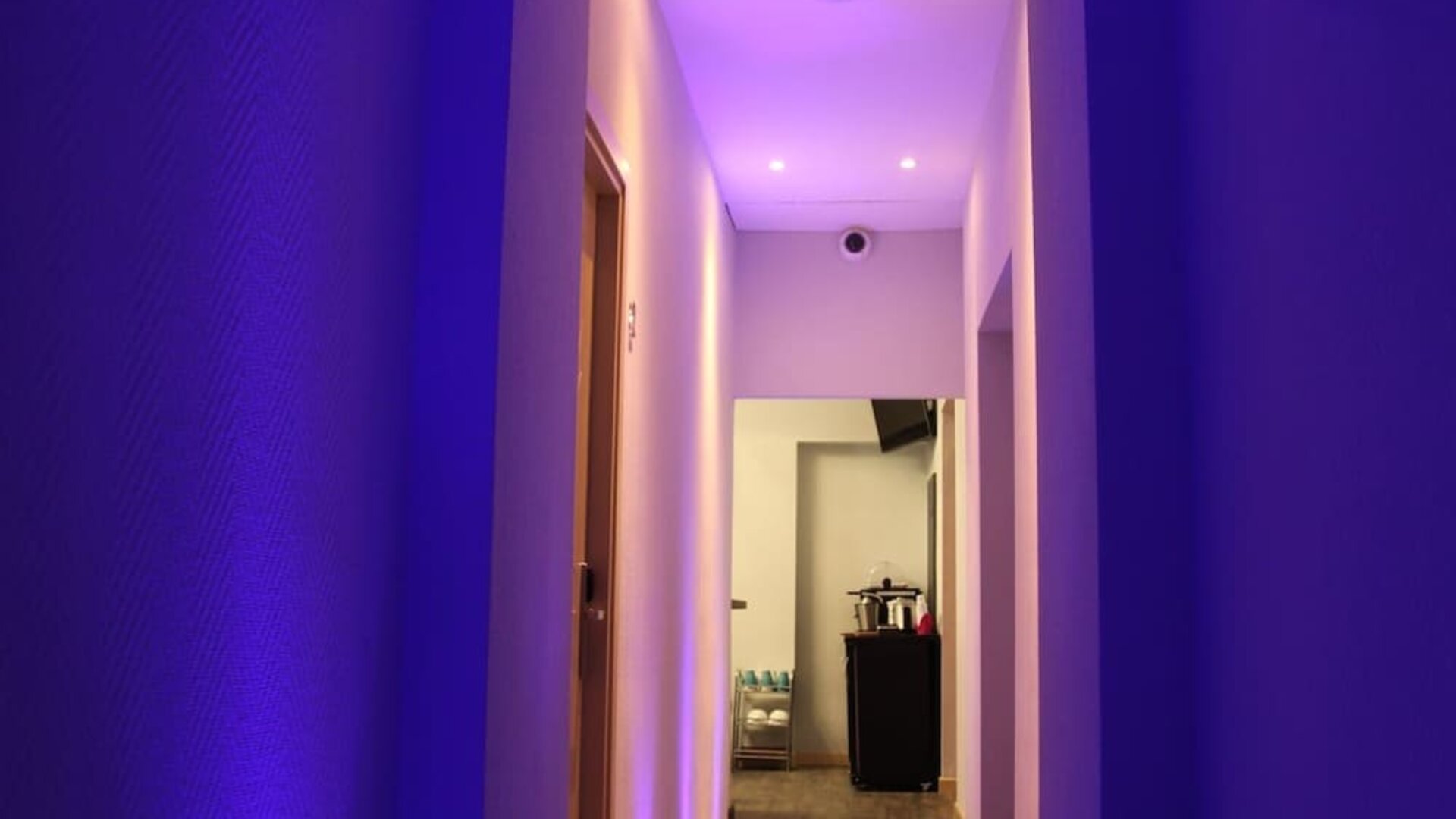 Contemporary hallway with ambient lighting leading to guest rooms at Dolce Vita Rooms & Breakfast.