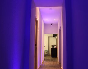 Contemporary hallway with ambient lighting leading to guest rooms at Dolce Vita Rooms & Breakfast.