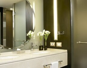 Modern bathroom with double vanity, illuminated mirror, walk-in shower and premium bath amenities at NH Buenos Aires 9 De Julio.