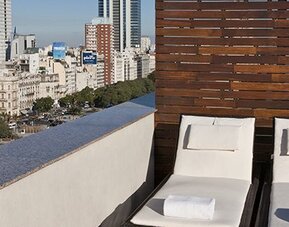 Rooftop sun terrace with comfortable loungers and panoramic city skyline views at NH Buenos Aires 9 De Julio.