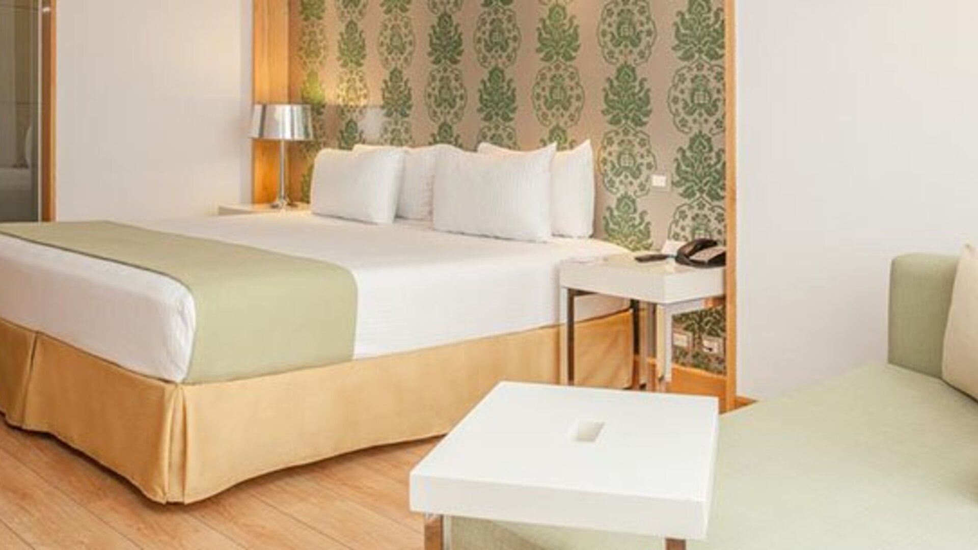 Spacious guest room with king bed, seating area and contemporary furnishings at NH Collection Mexico City Airport T2.