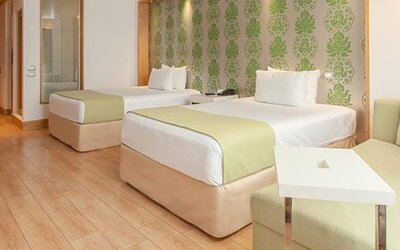Contemporary guest room with two double beds, sofa seating and modern amenities at NH Collection Mexico City Airport T2.