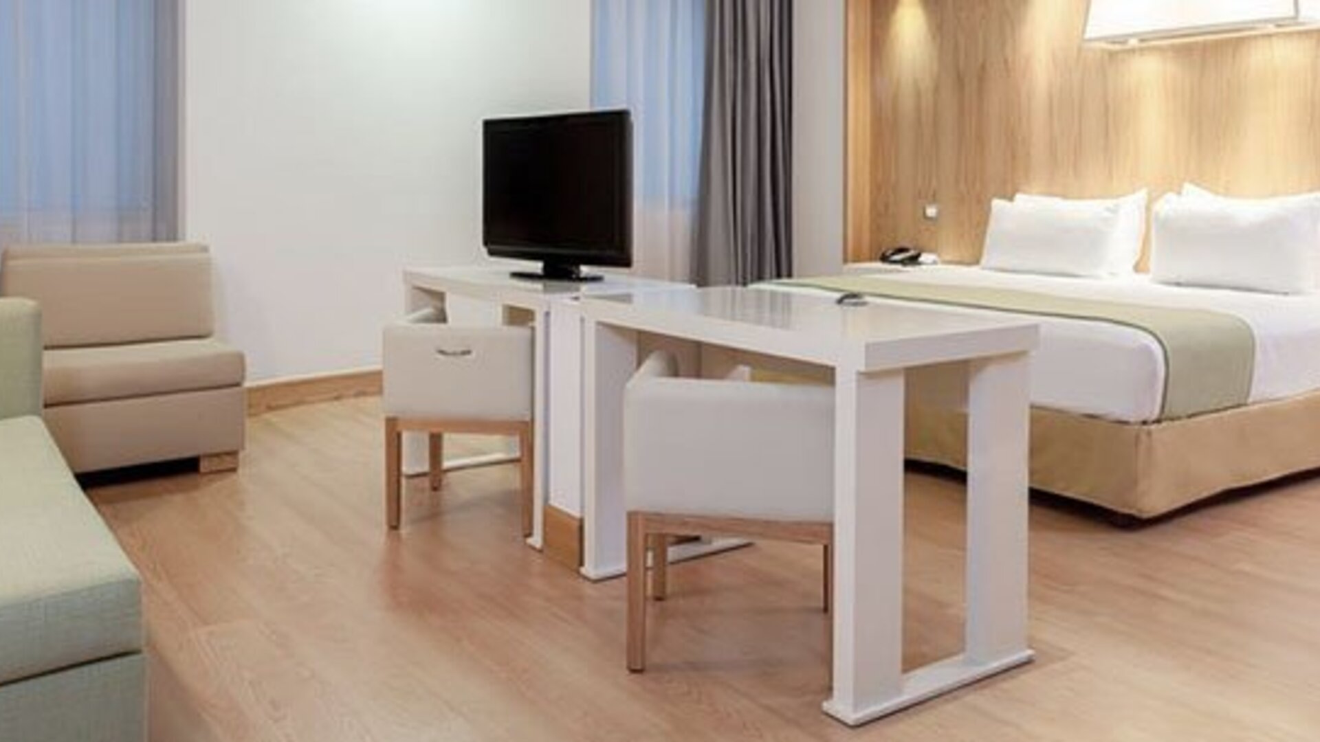 Spacious suite featuring king bed, dining area, lounge seating and contemporary design at NH Collection Mexico City Airport T2.