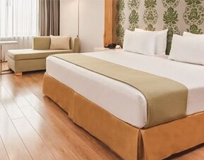 Bright guest room with king bed, chaise lounge, workspace and contemporary furnishings at NH Collection Mexico City Airport T2.