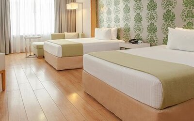 Spacious guest room with two double beds, seating area, large windows and modern décor at NH Collection Mexico City Airport T2.